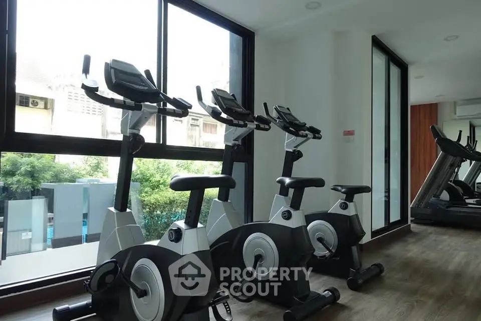 Modern gym with exercise bikes and large windows in a residential building.