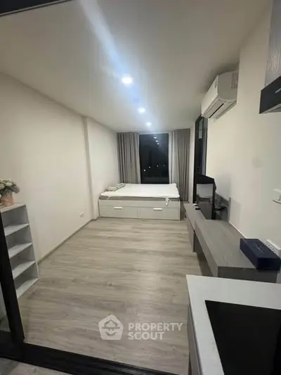 Modern studio apartment with sleek design and efficient layout, featuring a cozy bed and contemporary furnishings.
