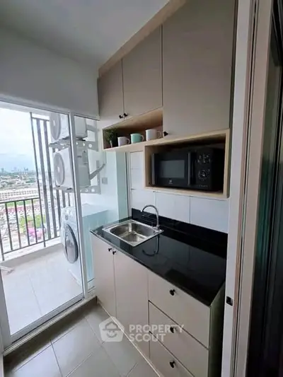 Compact kitchen with modern appliances and balcony view in urban apartment