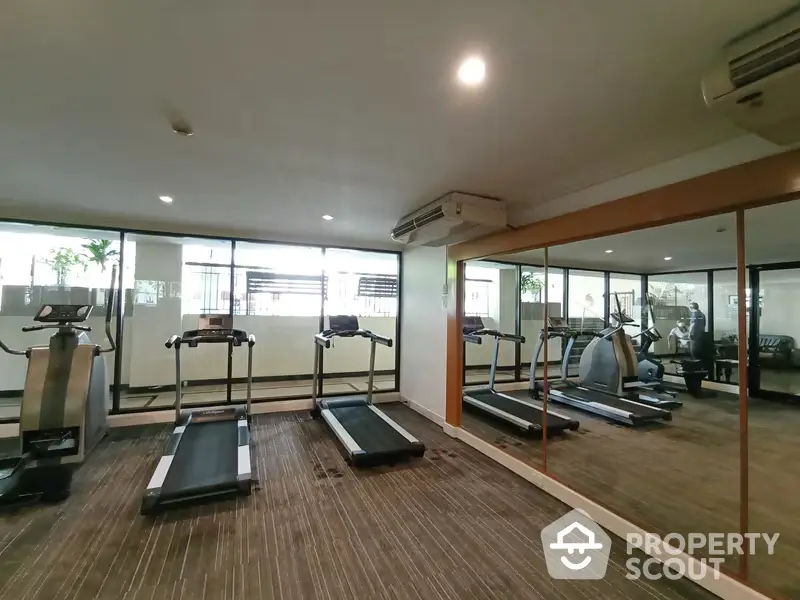 Spacious and well-equipped residential gym with modern fitness machines, ample lighting, and large mirrors, perfect for a healthy lifestyle.