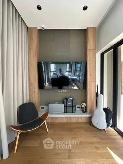 Stylish modern living room with wooden flooring, sleek TV setup, and elegant chair.