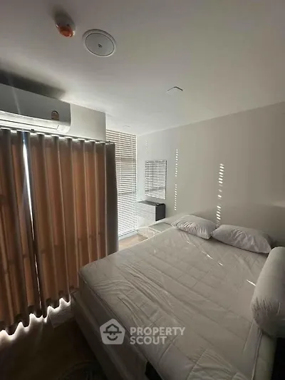 Cozy bedroom with natural light, featuring a comfortable bed and modern air conditioning unit.