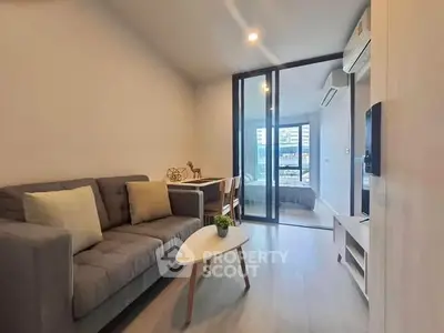 Modern living room with cozy sofa and stylish decor, featuring a view into a chic bedroom.