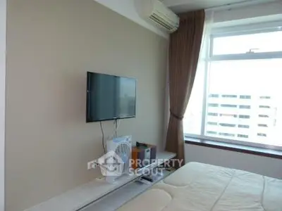 Modern bedroom with wall-mounted TV and large window offering city views.