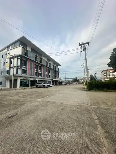 Modern multi-story building with spacious parking area and clear sky view.