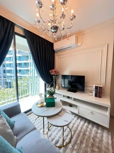 Elegant living room with chandelier, modern decor, and balcony view in luxury apartment.