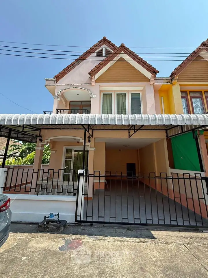 Charming two-story house with gated driveway and covered carport in a sunny neighborhood.