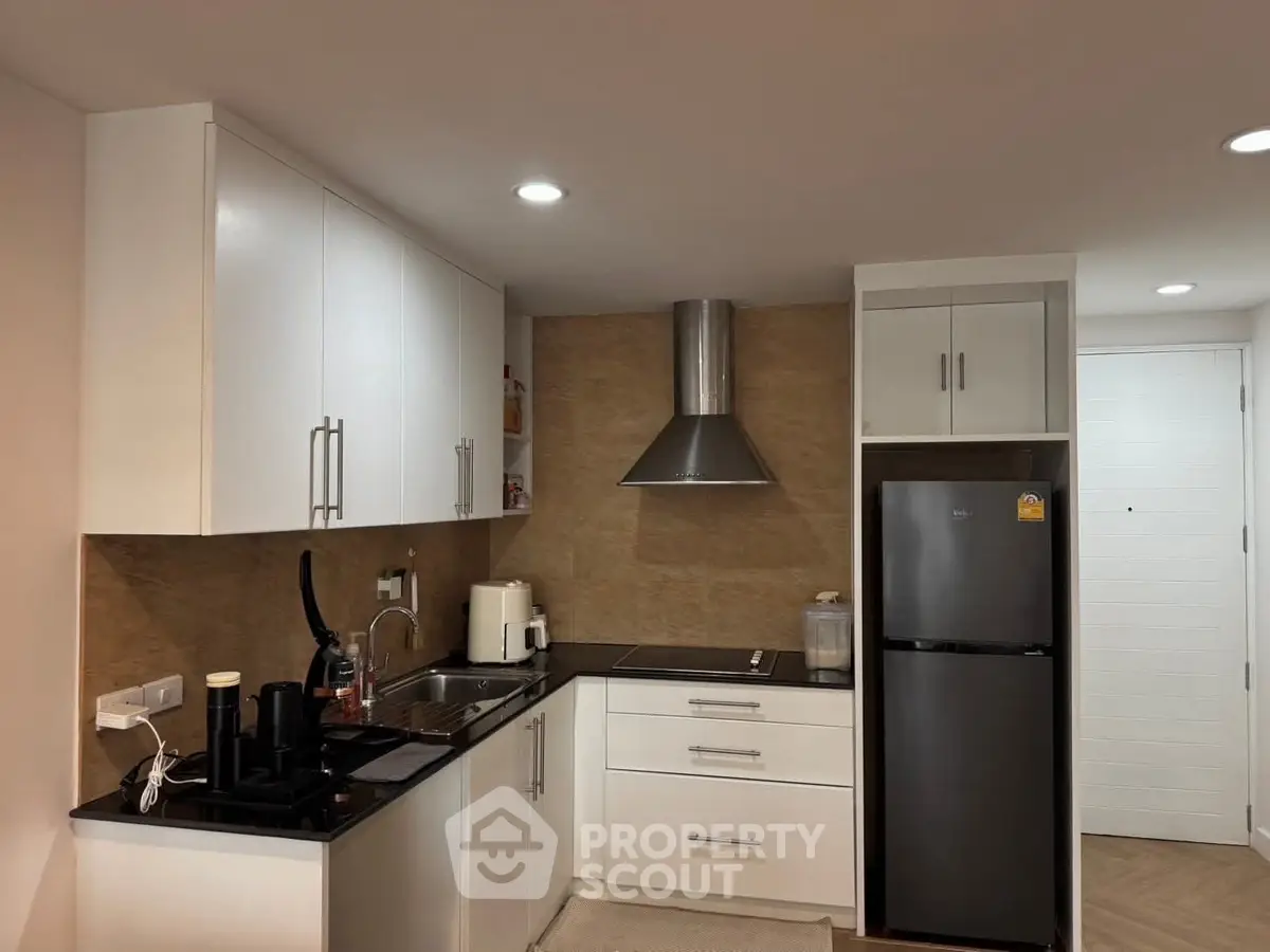 Modern kitchen with sleek cabinets and stainless steel appliances in a cozy apartment.