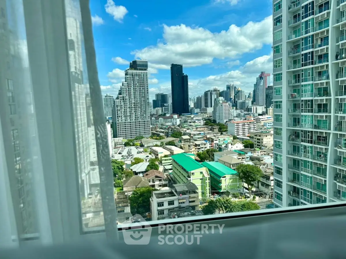Stunning cityscape view from high-rise apartment window with clear blue sky.