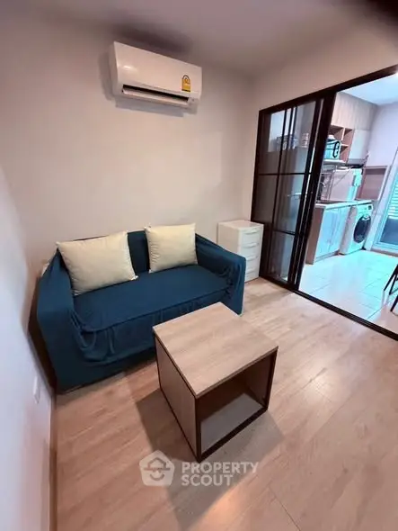 Cozy living room with modern air conditioning and compact kitchen view, perfect for urban living.
