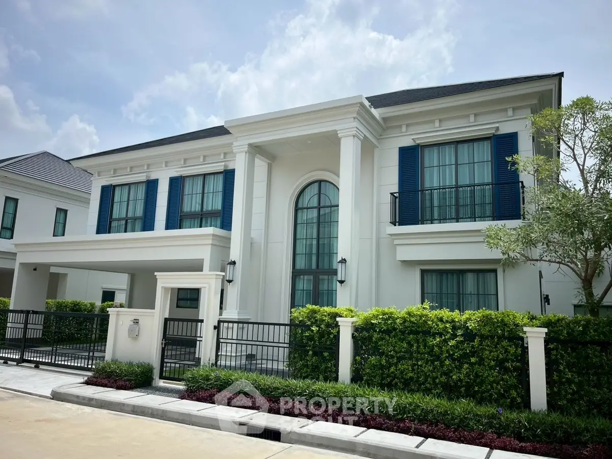 Elegant two-story white house with blue shutters and lush landscaping