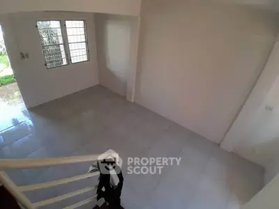 Spacious empty room with tiled floor and large window, ideal for customization.