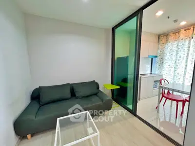 Modern compact living room with glass partition and stylish kitchen area.
