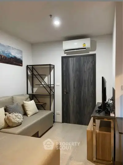 Modern living room with cozy sofa, wall-mounted TV, and air conditioning unit.
