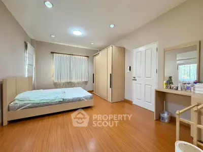 Spacious bedroom with wooden flooring and modern furniture, perfect for relaxation and comfort.