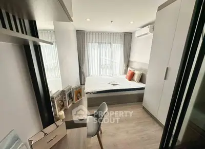 Modern bedroom with stylish decor and ample natural light, featuring a cozy bed and sleek furniture.