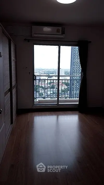 Spacious room with wooden flooring and balcony offering stunning city views.
