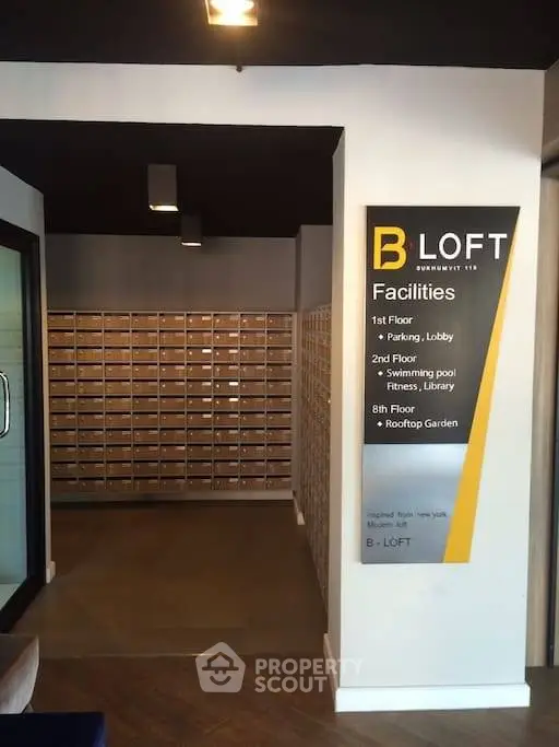Modern apartment building lobby with mailboxes and facility sign, showcasing amenities like pool and rooftop garden.