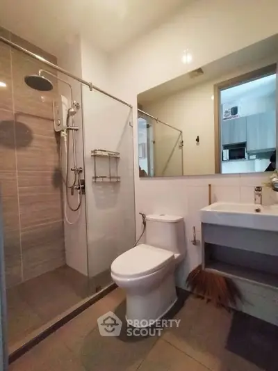 Modern bathroom with glass shower and sleek fixtures in contemporary apartment.