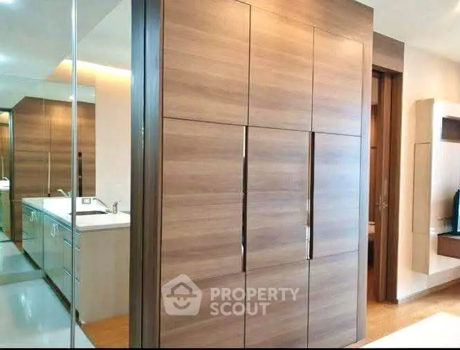 Modern interior with sleek wooden cabinetry and mirrored accents in a stylish apartment.