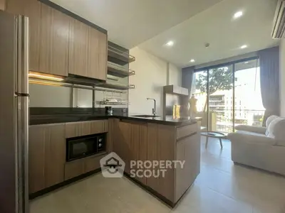 Modern open-layout kitchen with sleek cabinetry and cozy living area, featuring large windows for natural light.