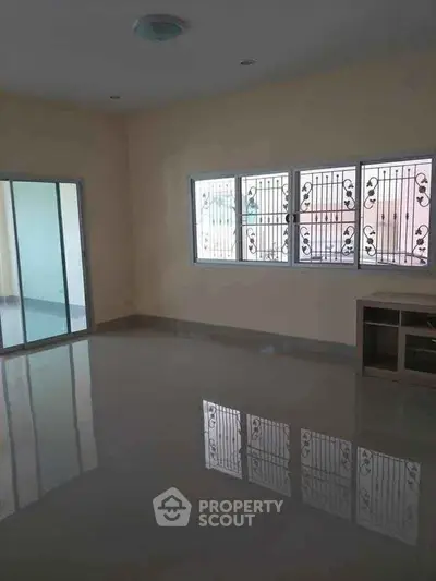 Spacious empty living room with large windows and sliding glass doors.