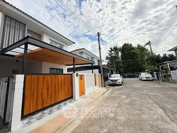 Modern residential street with contemporary homes and parked cars under a cloudy sky.