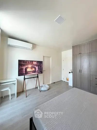 Modern bedroom with sleek furniture and air conditioning, featuring a stylish TV setup and ample storage space.