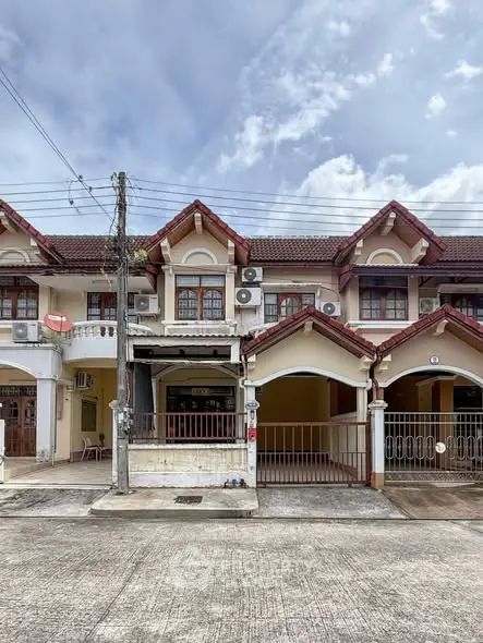 Charming townhouse exterior with classic red roof and multiple air conditioning units, perfect for family living.