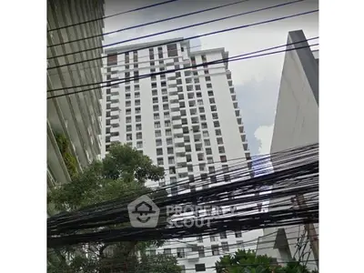 Modern high-rise building with urban view and lush greenery.