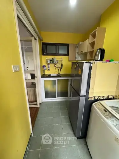Compact kitchen with bright yellow walls, modern appliances, and efficient storage solutions.