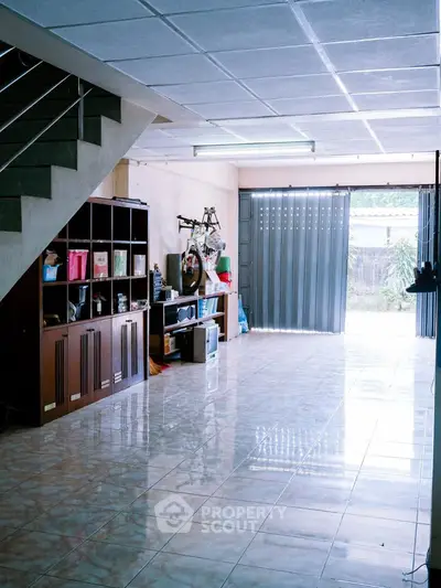Spacious tiled room with storage and open garage door, ideal for versatile use.