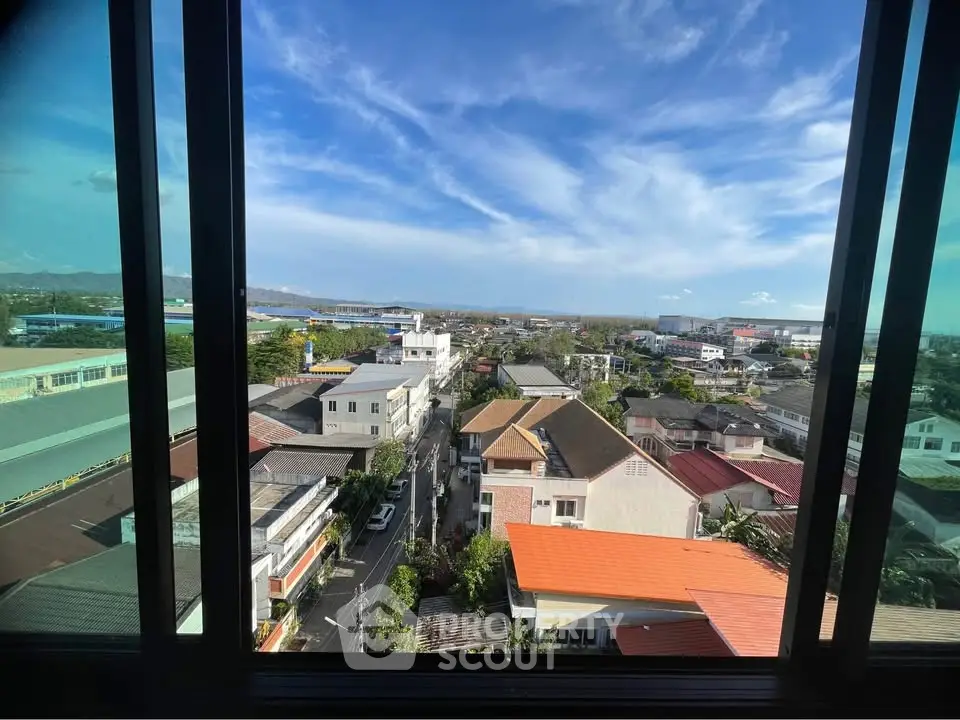 Stunning cityscape view from high-rise window showcasing vibrant rooftops and clear blue sky.