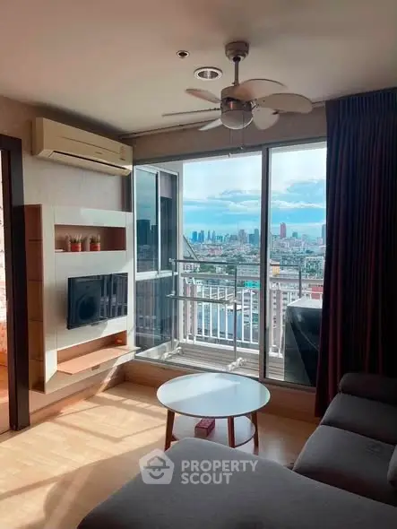 Modern living room with city view and balcony access in high-rise apartment.