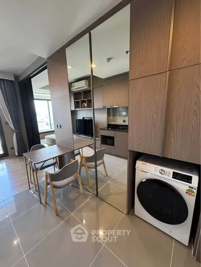 Modern apartment interior with sleek kitchen and dining area, featuring built-in appliances and stylish wood finishes.