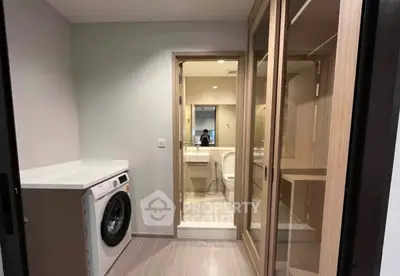 Modern laundry area with washing machine and mirrored closet in sleek apartment.