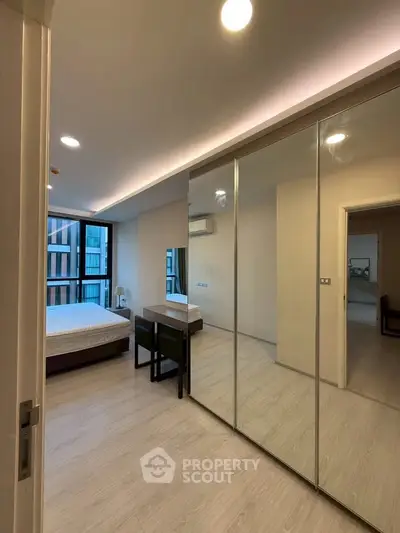 Modern bedroom with mirrored closet doors and sleek design in a contemporary apartment.