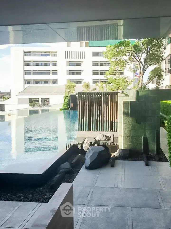 Luxurious apartment complex with serene pool and modern architecture.