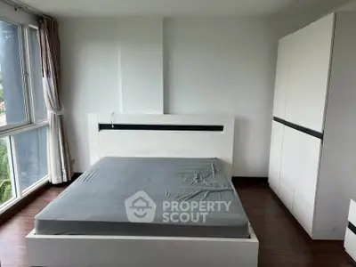 Spacious bedroom with large windows and modern furniture in a stylish apartment.