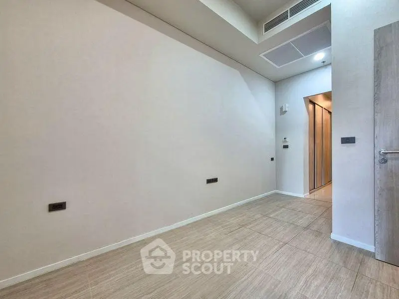 Spacious empty room with modern tile flooring and recessed lighting