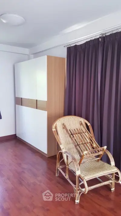 Cozy bedroom corner with wooden flooring and wicker chair