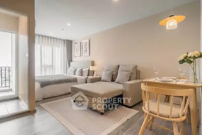 Modern open-plan living room with cozy seating and dining area, featuring a bright bedroom and balcony view.