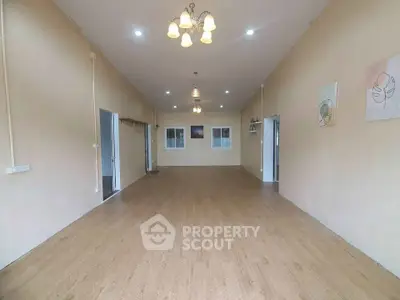 Spacious empty room with wooden flooring and elegant lighting, perfect for customization.