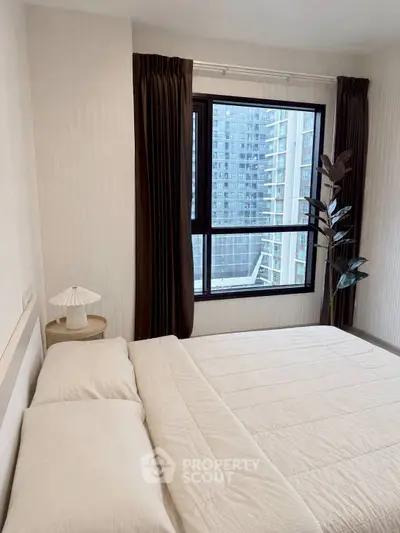 Modern bedroom with large window and city view, featuring minimalist decor and cozy bedding.