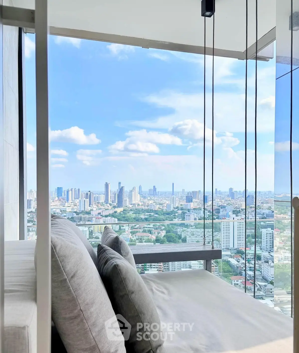 Stunning city view from a modern high-rise apartment with cozy seating area.