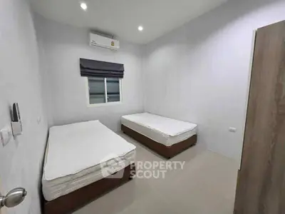 Minimalist bedroom with twin beds and air conditioning in modern apartment.