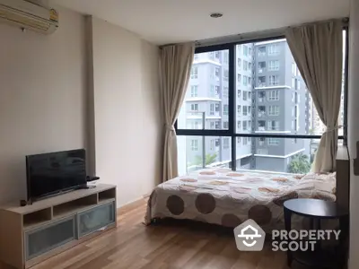 Modern bedroom with large window and city view in a high-rise apartment.