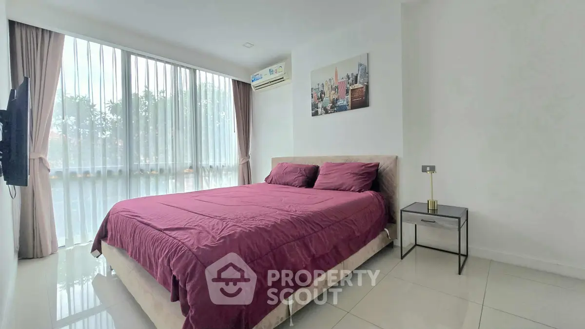 Modern bedroom with large window and stylish decor in a bright apartment.