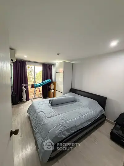 Spacious bedroom with modern decor and large window for natural light.