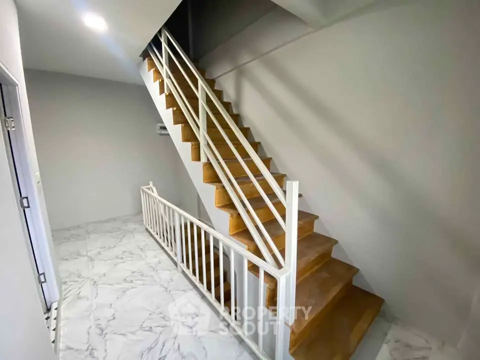 Modern staircase with sleek white railings and marble flooring in a contemporary building.